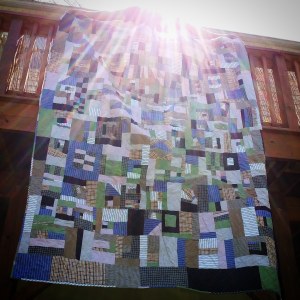 Quilt made from old shirts in a random pattern hung from deck with sunburst